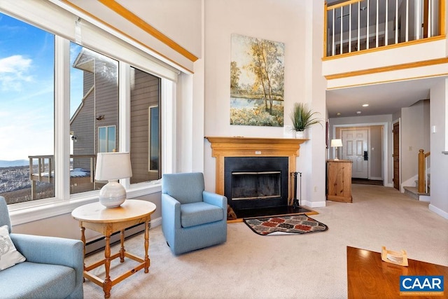 living area with a towering ceiling, carpet, and baseboard heating