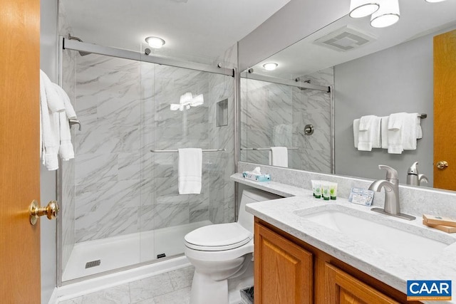 bathroom featuring a shower with door, vanity, and toilet