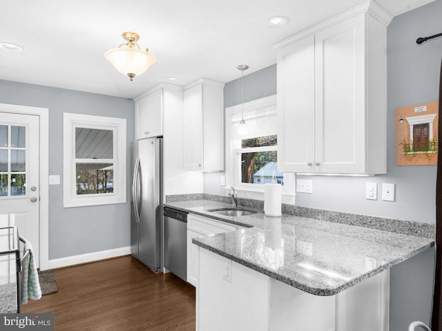 kitchen featuring sink, hanging light fixtures, stainless steel appliances, white cabinets, and kitchen peninsula