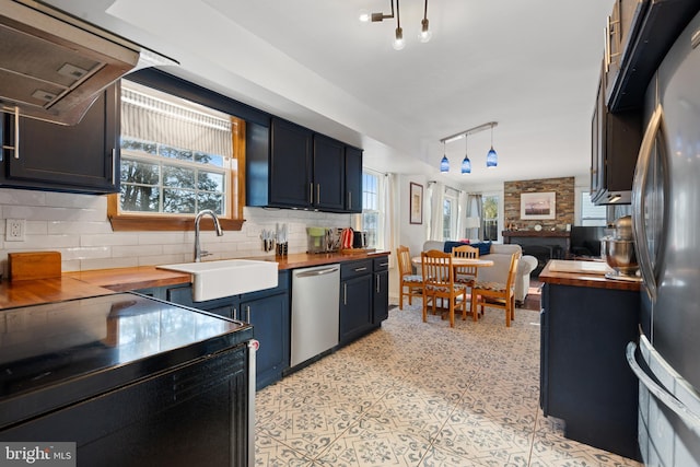 kitchen featuring butcher block countertops, hanging light fixtures, sink, and appliances with stainless steel finishes