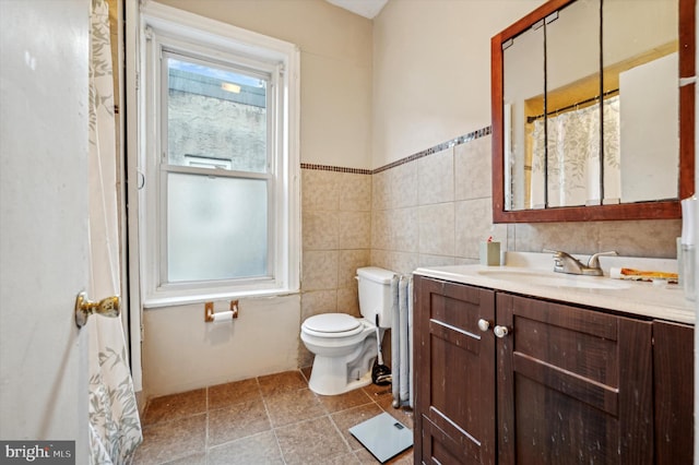 bathroom featuring vanity, toilet, and tile walls