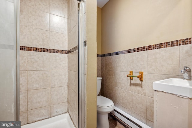 bathroom featuring tile walls, vanity, a baseboard heating unit, tiled shower, and toilet