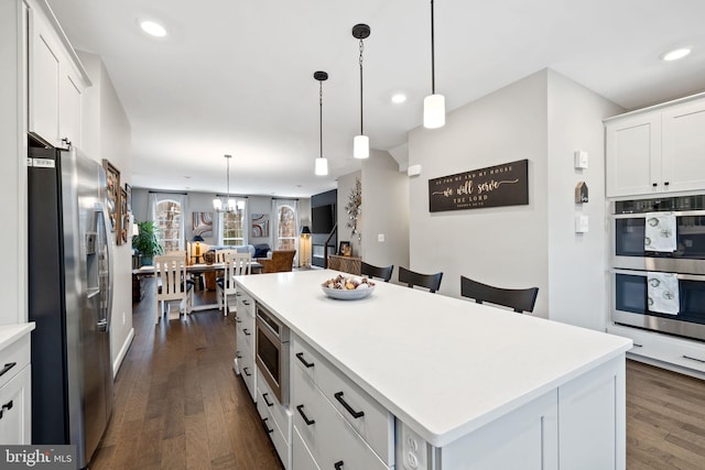 kitchen with a kitchen island, appliances with stainless steel finishes, pendant lighting, and white cabinets