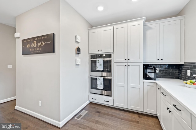 kitchen featuring double oven, backsplash, dark hardwood / wood-style floors, and white cabinets