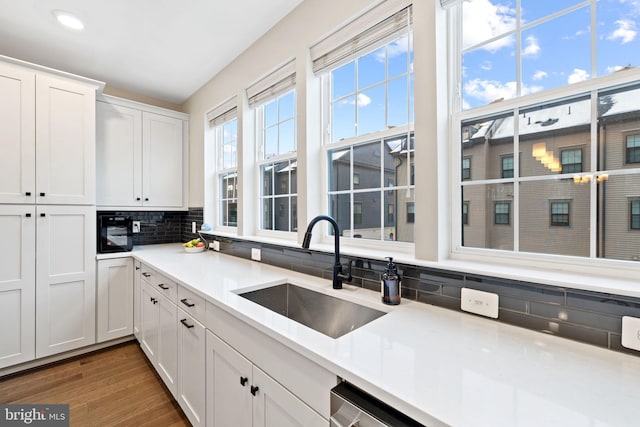 kitchen featuring backsplash, dark wood-type flooring, sink, and white cabinets