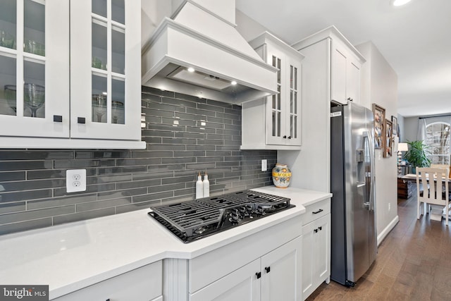 kitchen with premium range hood, black gas cooktop, white cabinetry, decorative backsplash, and stainless steel fridge with ice dispenser