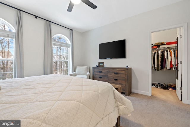 carpeted bedroom with a spacious closet, ceiling fan, and a closet