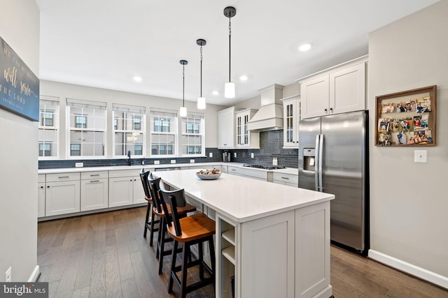 kitchen featuring custom exhaust hood, stainless steel appliances, a center island, and white cabinets