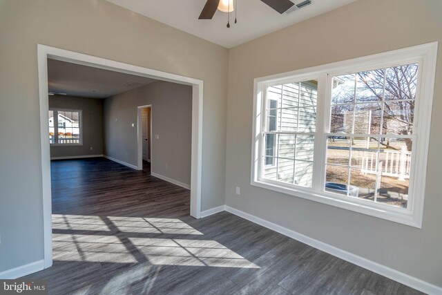 spare room featuring a ceiling fan, dark wood-style flooring, visible vents, and baseboards