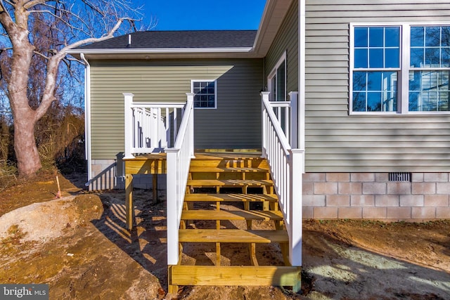 view of exterior entry featuring crawl space and a shingled roof