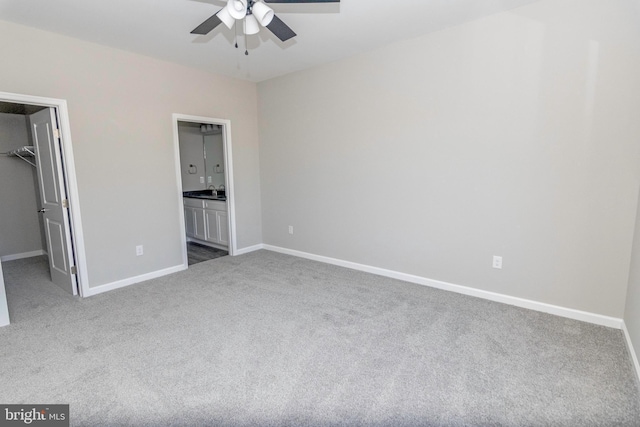 unfurnished bedroom featuring a closet, a spacious closet, carpet flooring, ensuite bath, and baseboards