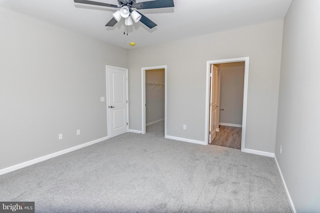 unfurnished bedroom with carpet floors, baseboards, a walk in closet, and a closet