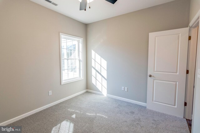 empty room featuring carpet floors, baseboards, visible vents, and a ceiling fan