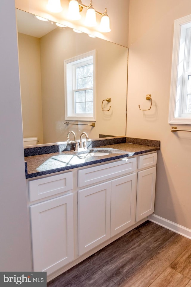 half bathroom featuring vanity, a wealth of natural light, and wood finished floors