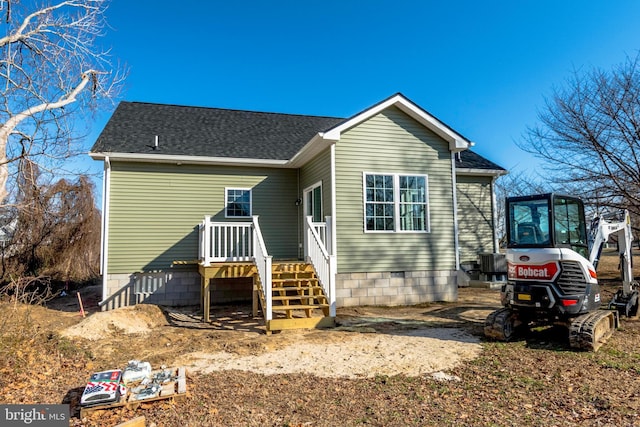 rear view of house featuring central air condition unit and a shingled roof