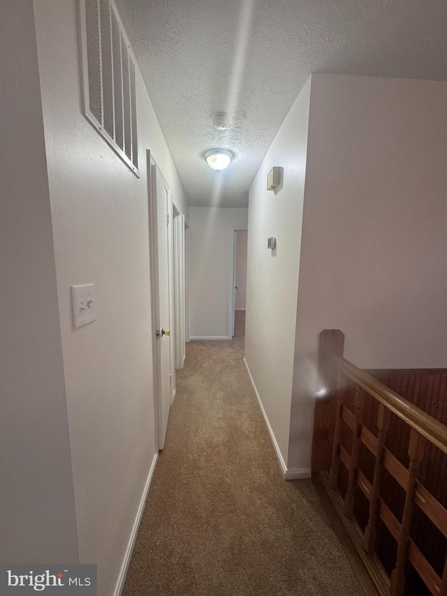 corridor with carpet flooring and a textured ceiling