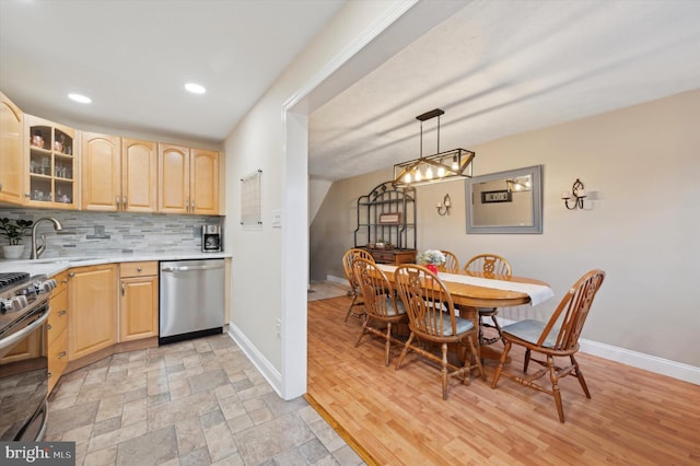 kitchen with pendant lighting, sink, stainless steel appliances, tasteful backsplash, and light brown cabinetry