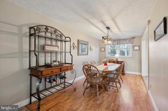 dining room featuring an inviting chandelier, a textured ceiling, and light wood-type flooring