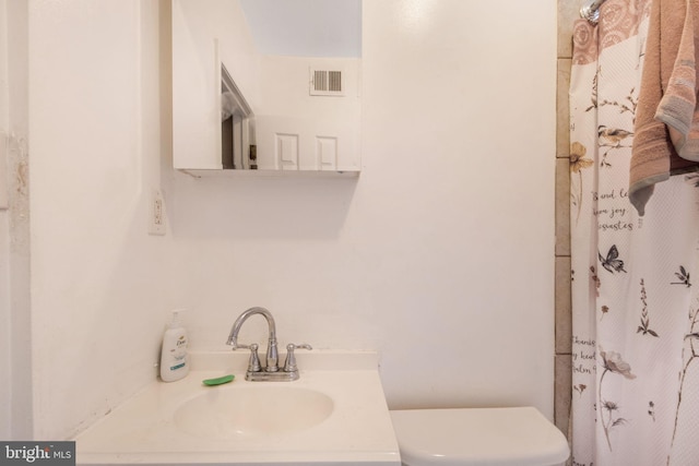 bathroom featuring vanity, toilet, and curtained shower