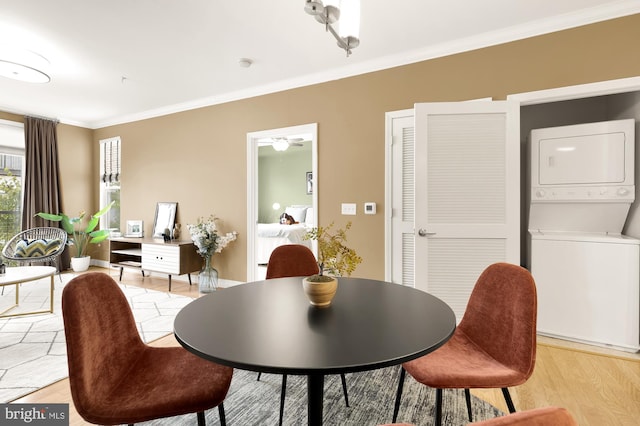 dining space featuring stacked washer and dryer, ornamental molding, and light hardwood / wood-style flooring