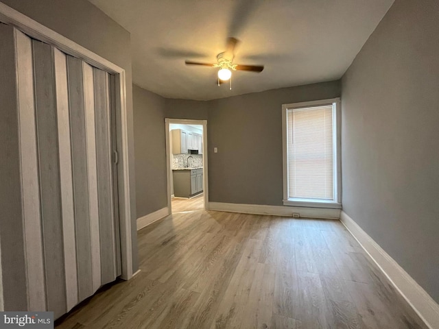 unfurnished room featuring sink, light hardwood / wood-style floors, and ceiling fan