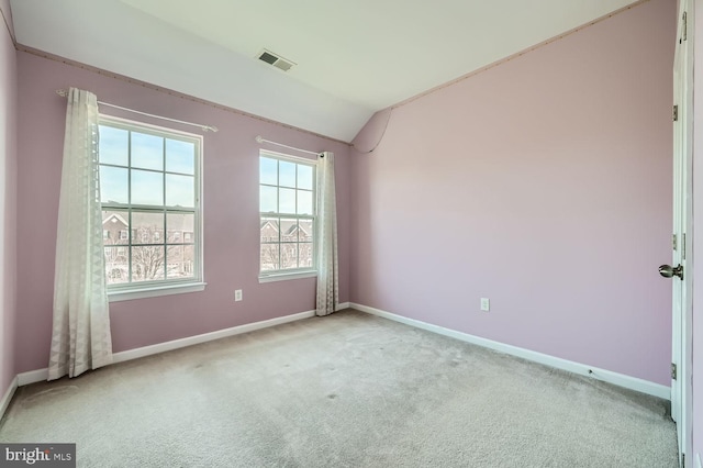 empty room featuring light colored carpet and vaulted ceiling