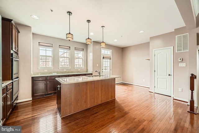 kitchen with an island with sink, dark hardwood / wood-style floors, and pendant lighting