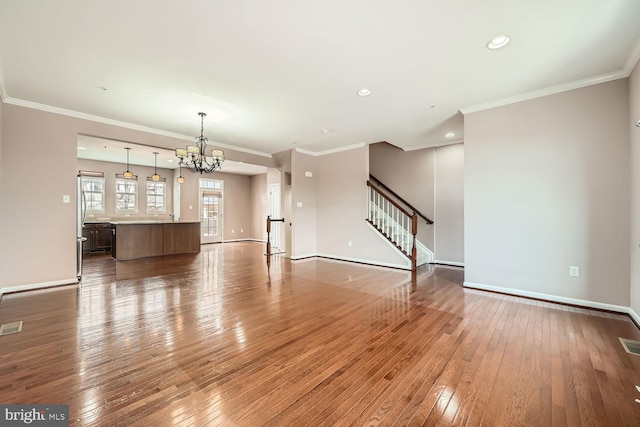 unfurnished living room featuring crown molding, a chandelier, and hardwood / wood-style floors