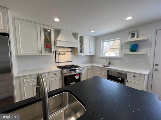 kitchen featuring white cabinetry, sink, stainless steel appliances, and premium range hood