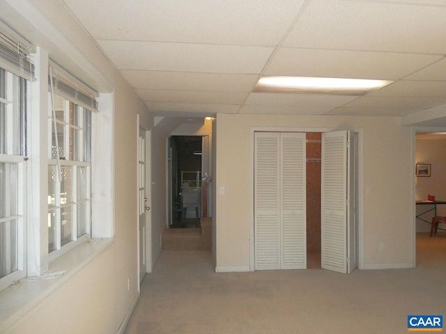 corridor with a paneled ceiling and carpet floors