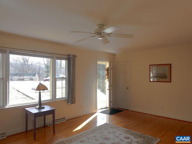 entrance foyer featuring ornamental molding, ceiling fan, and light wood-type flooring