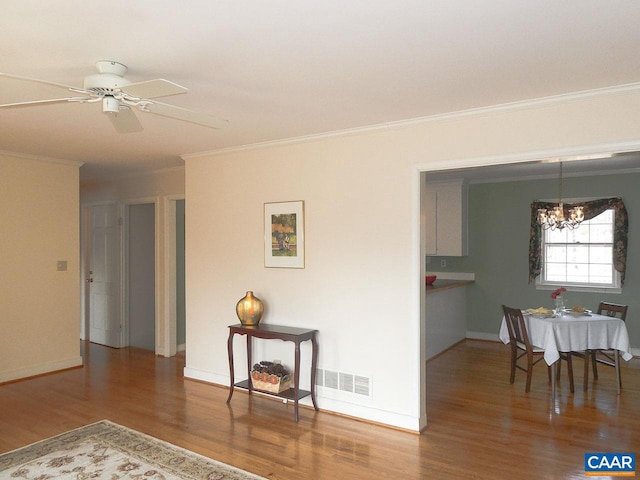 interior space featuring hardwood / wood-style floors, ceiling fan with notable chandelier, and ornamental molding