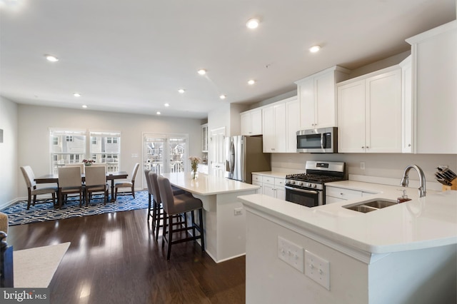 kitchen with sink, a center island, a kitchen breakfast bar, stainless steel appliances, and white cabinets