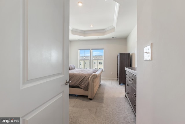 bedroom with light carpet, crown molding, and a raised ceiling