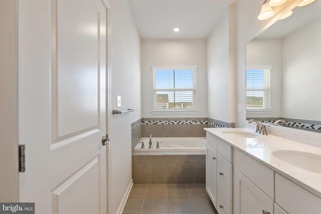 bathroom with a relaxing tiled tub, vanity, tile patterned flooring, and a wealth of natural light