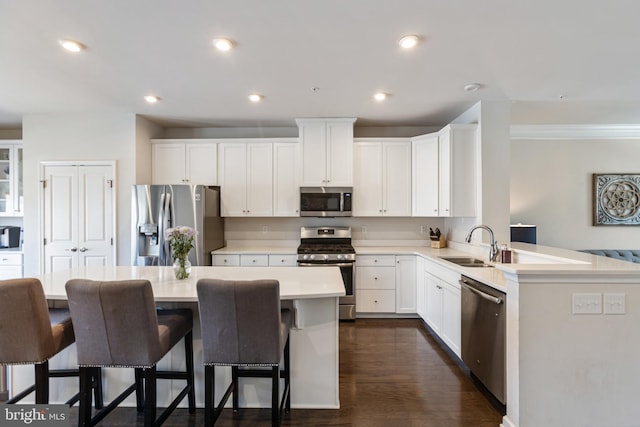 kitchen featuring stainless steel appliances, kitchen peninsula, white cabinets, and a kitchen bar