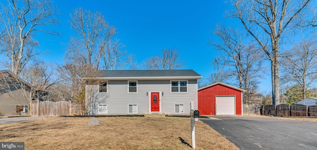 bi-level home with an outdoor structure, a front yard, driveway, and a detached garage