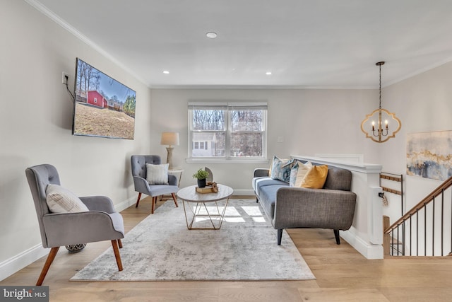 living area featuring ornamental molding, light wood-type flooring, a notable chandelier, and baseboards