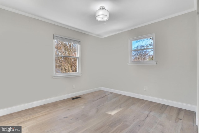 empty room featuring ornamental molding, light wood-style flooring, and baseboards