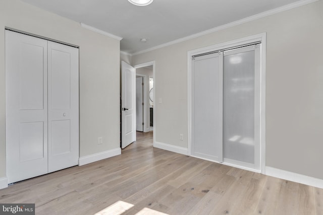 unfurnished bedroom featuring light wood-style floors, crown molding, baseboards, and two closets