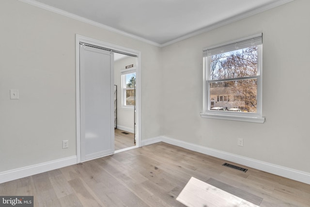 unfurnished bedroom featuring ornamental molding, visible vents, light wood-style flooring, and multiple windows