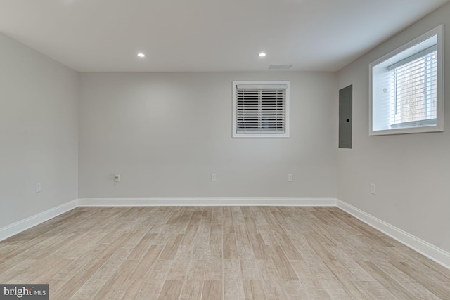 empty room featuring light wood finished floors, electric panel, and baseboards