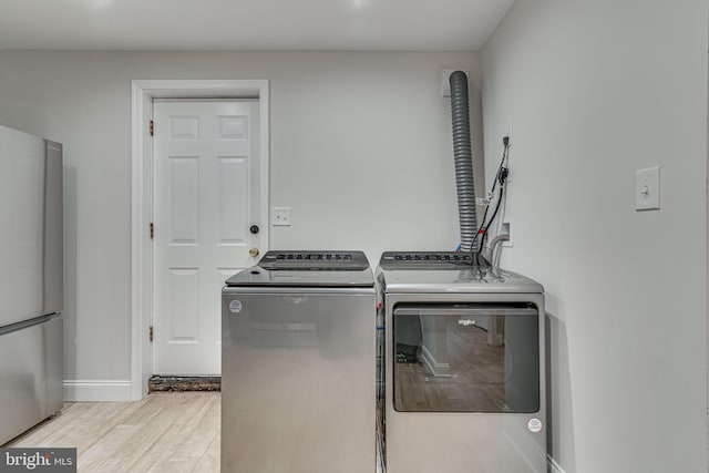 washroom featuring light wood-style floors, laundry area, baseboards, and separate washer and dryer