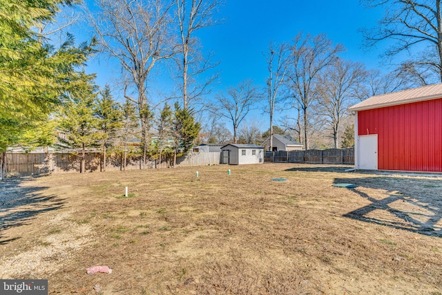 view of yard featuring an outbuilding, a fenced backyard, and a storage unit