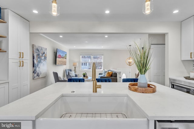 kitchen featuring open shelves, light countertops, a sink, and decorative light fixtures