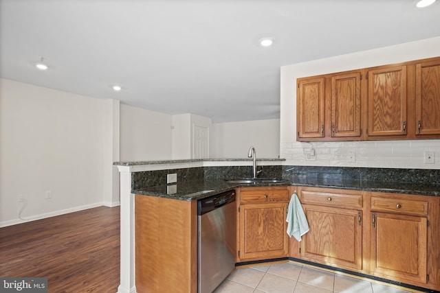 kitchen with sink, dark stone countertops, tasteful backsplash, stainless steel dishwasher, and kitchen peninsula