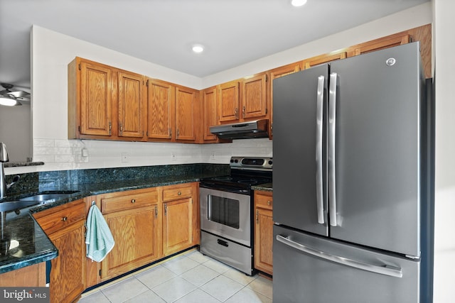 kitchen featuring light tile patterned flooring, appliances with stainless steel finishes, sink, dark stone countertops, and decorative backsplash