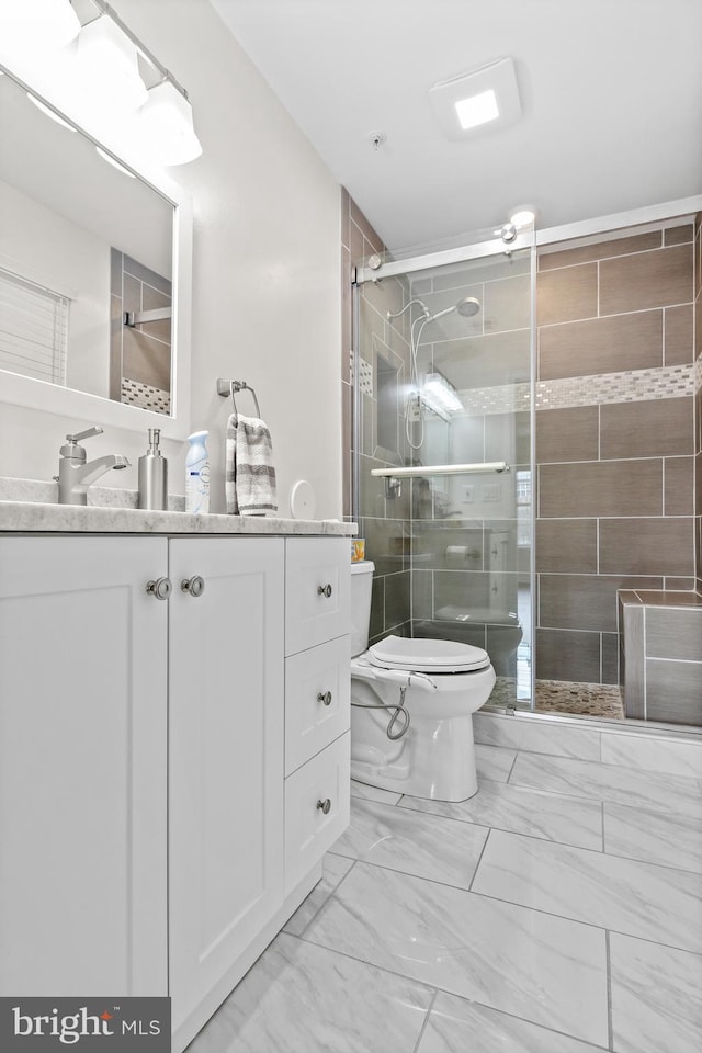 bathroom featuring vanity, a shower with door, and toilet