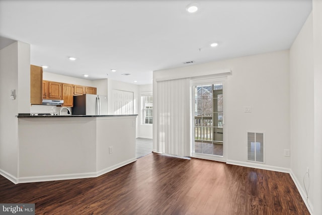 kitchen featuring dark wood-type flooring, stainless steel fridge, kitchen peninsula, and decorative backsplash