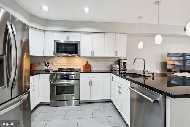 kitchen featuring decorative light fixtures, white cabinetry, sink, kitchen peninsula, and stainless steel appliances